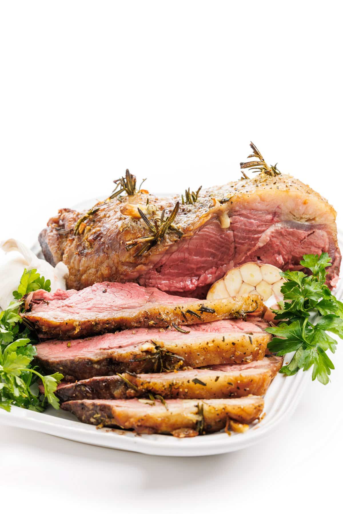 Sliced Garlic and rosemary studded beef roast on a platter.
