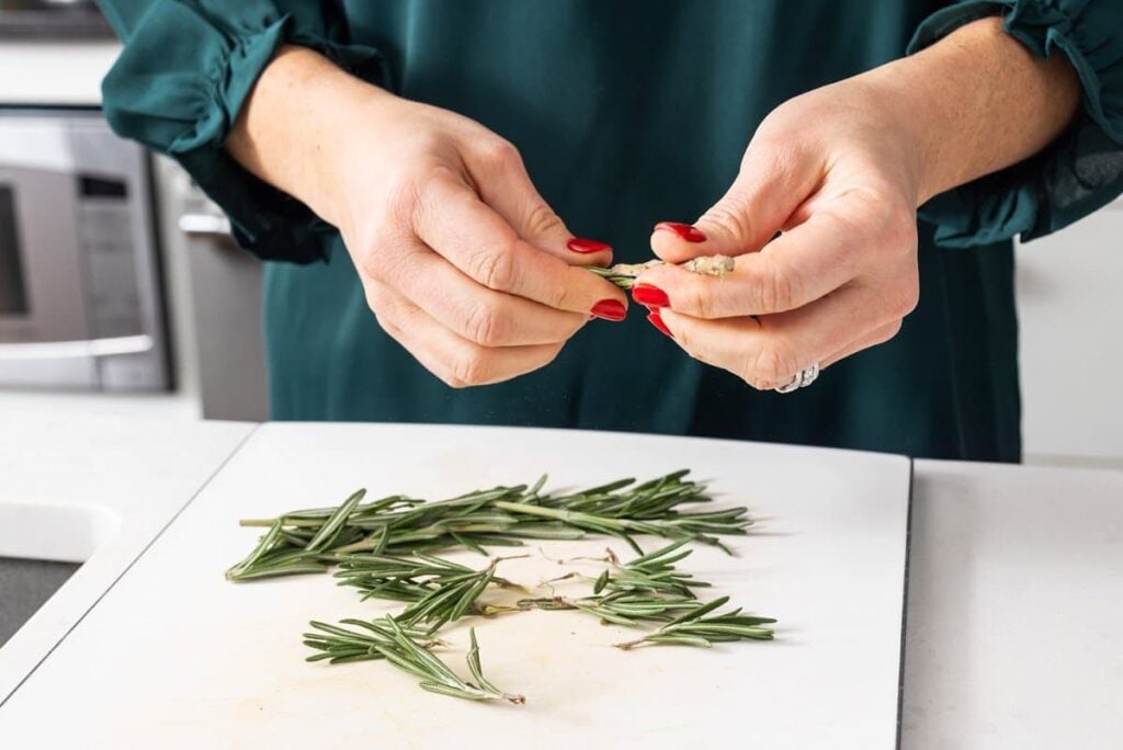 Liz take rosemary and breaking it into smaller sprigs.