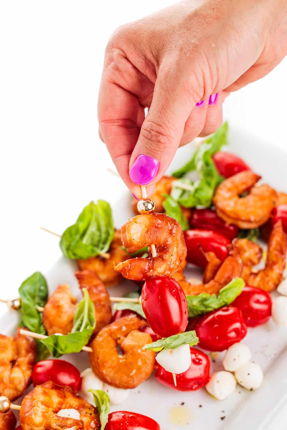 Holding a smoked shrimp caprese skewer.