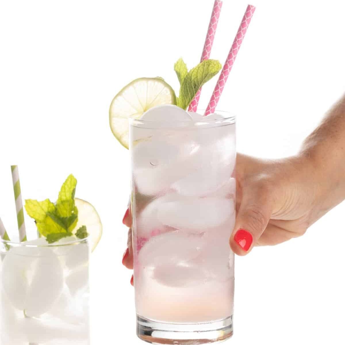 a hand holding a glass of ice and a straw