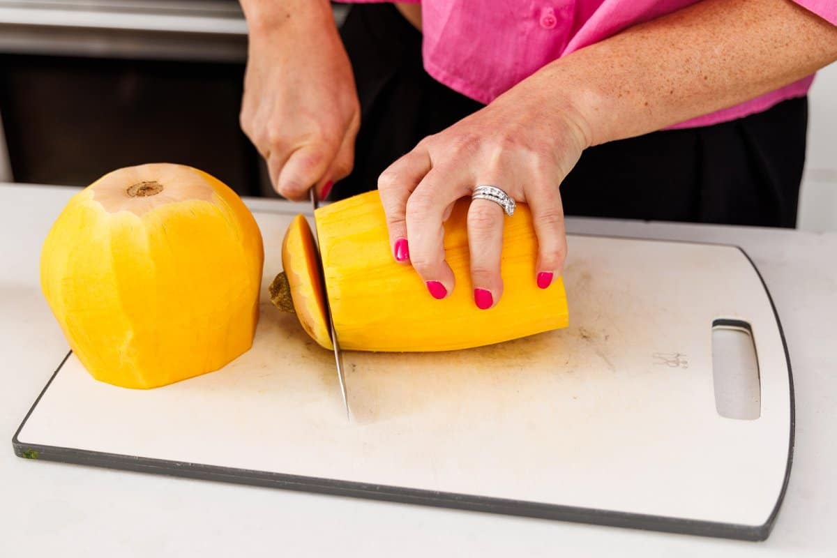 Liz cutting a peeled butternut squash into halves.