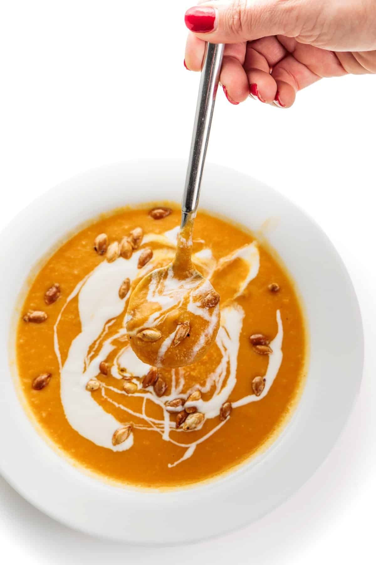 Spoonful of roasted root vegetable soup hovering over the bowl.