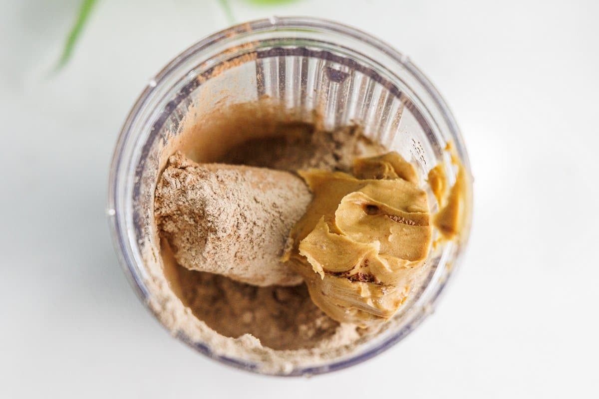 All of the ingredients for a chocolate peanut butter protein smoothie in a blender bowl.