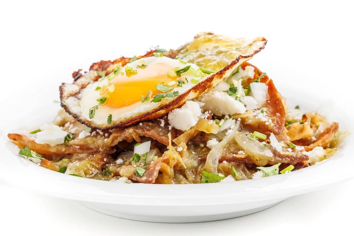 Chilaquiles verdes topped with a fried egg and fresh cilantro.