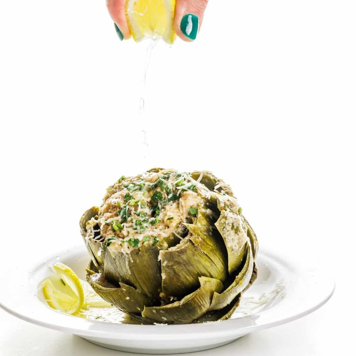 Garnishing Italian stuffed artichokes with lemon juice.