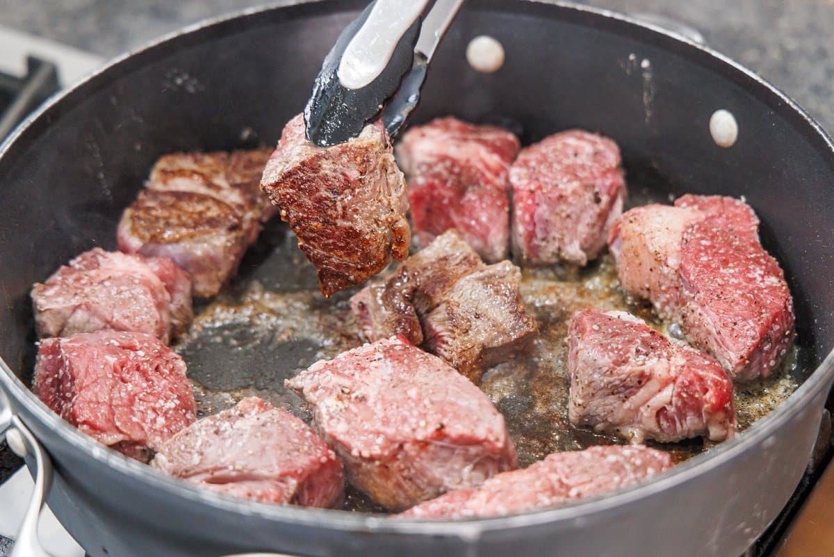 Searing beef pieces in a pan.