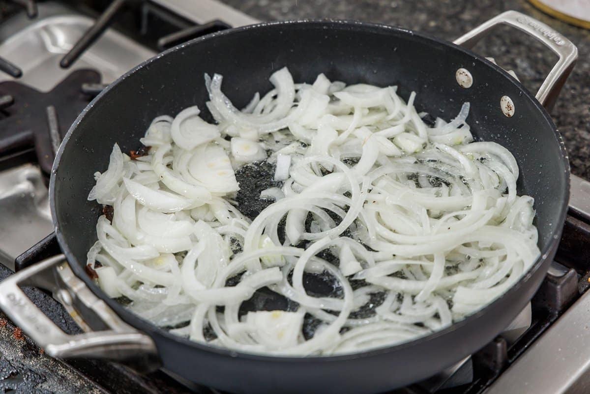 Sautéing onions in a frying pan on the stove.