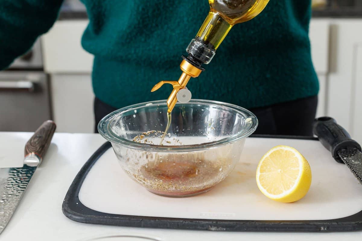 Adding olive oil to a medium sized glass bowl.