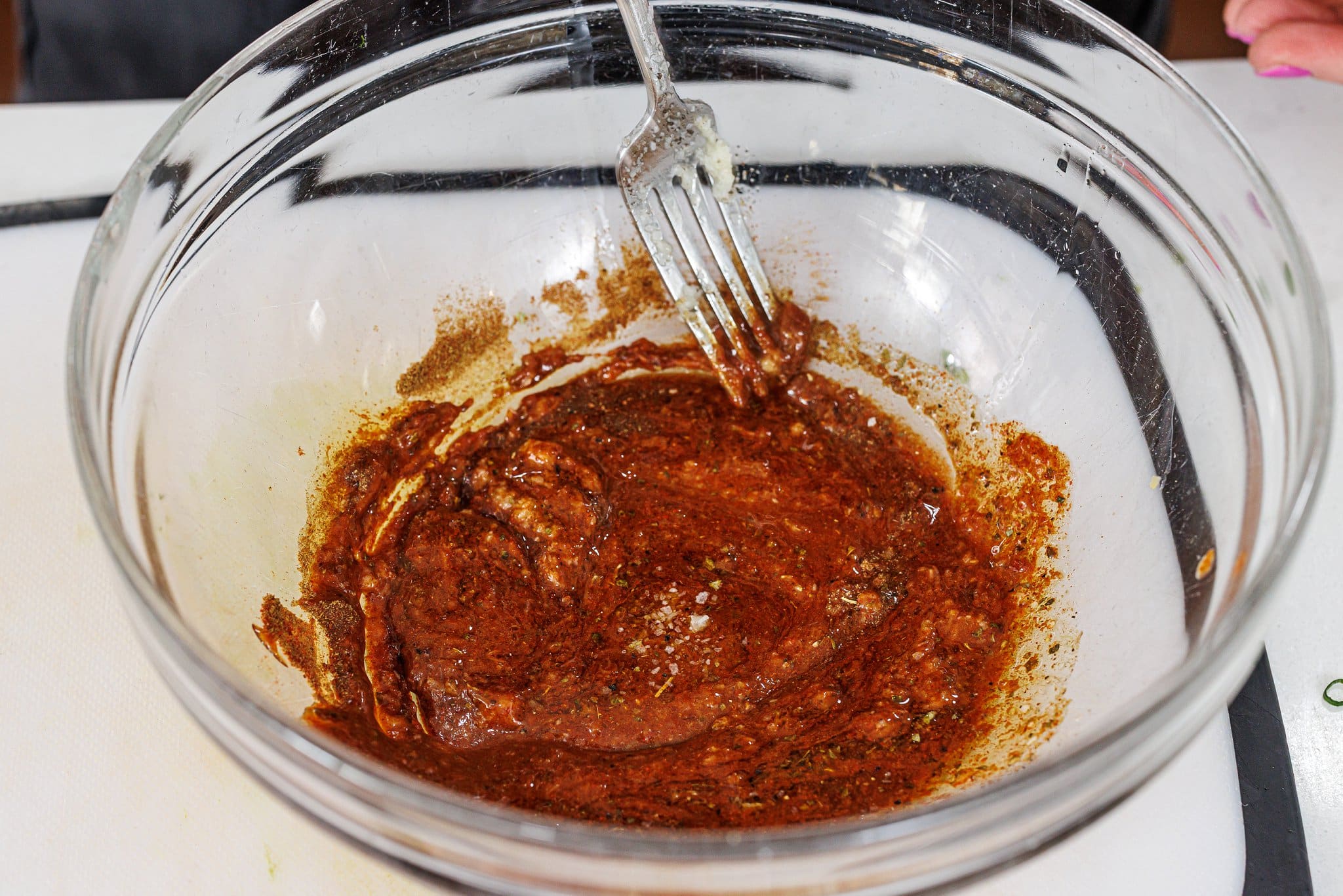 Whisking marinade together in a glass bowl with a fork.