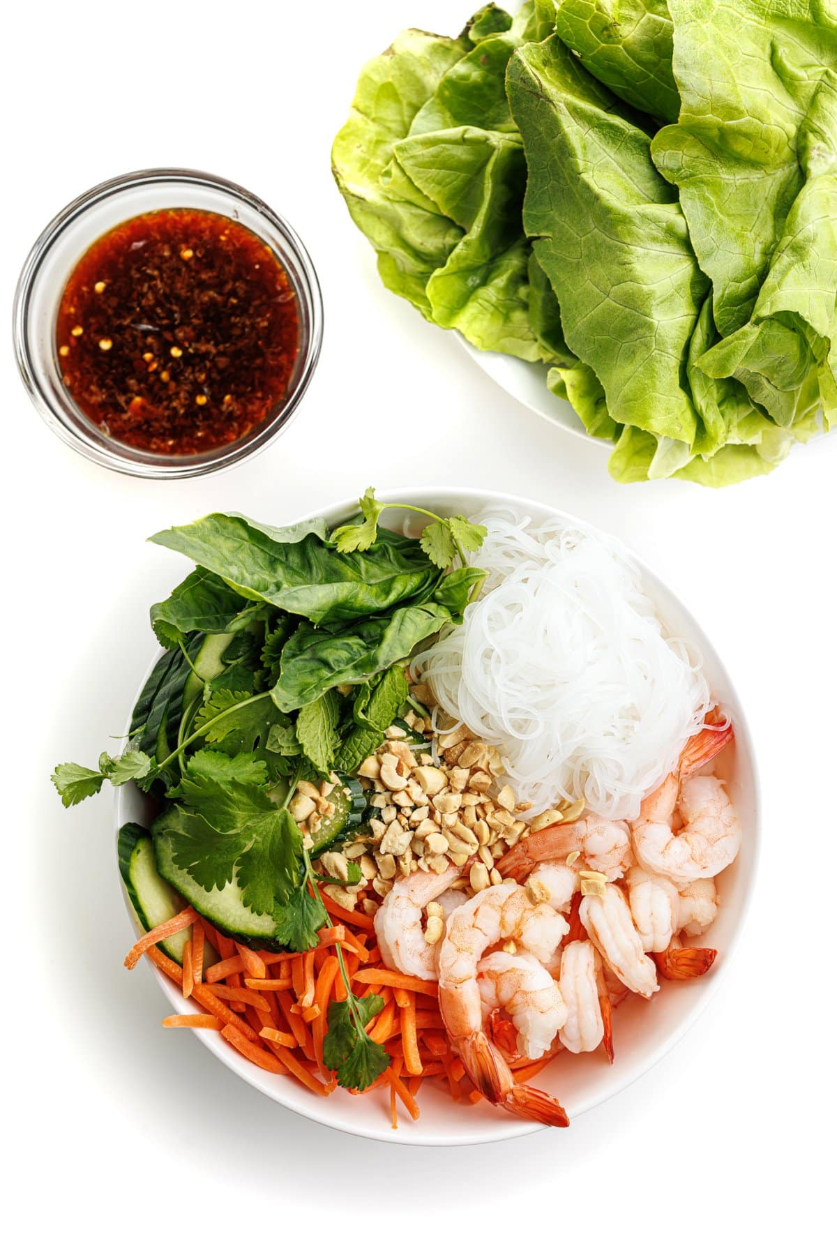 Vietnamese shrimp noodle bowl next to a head of bibb lettuce and a bowl of sauce.
