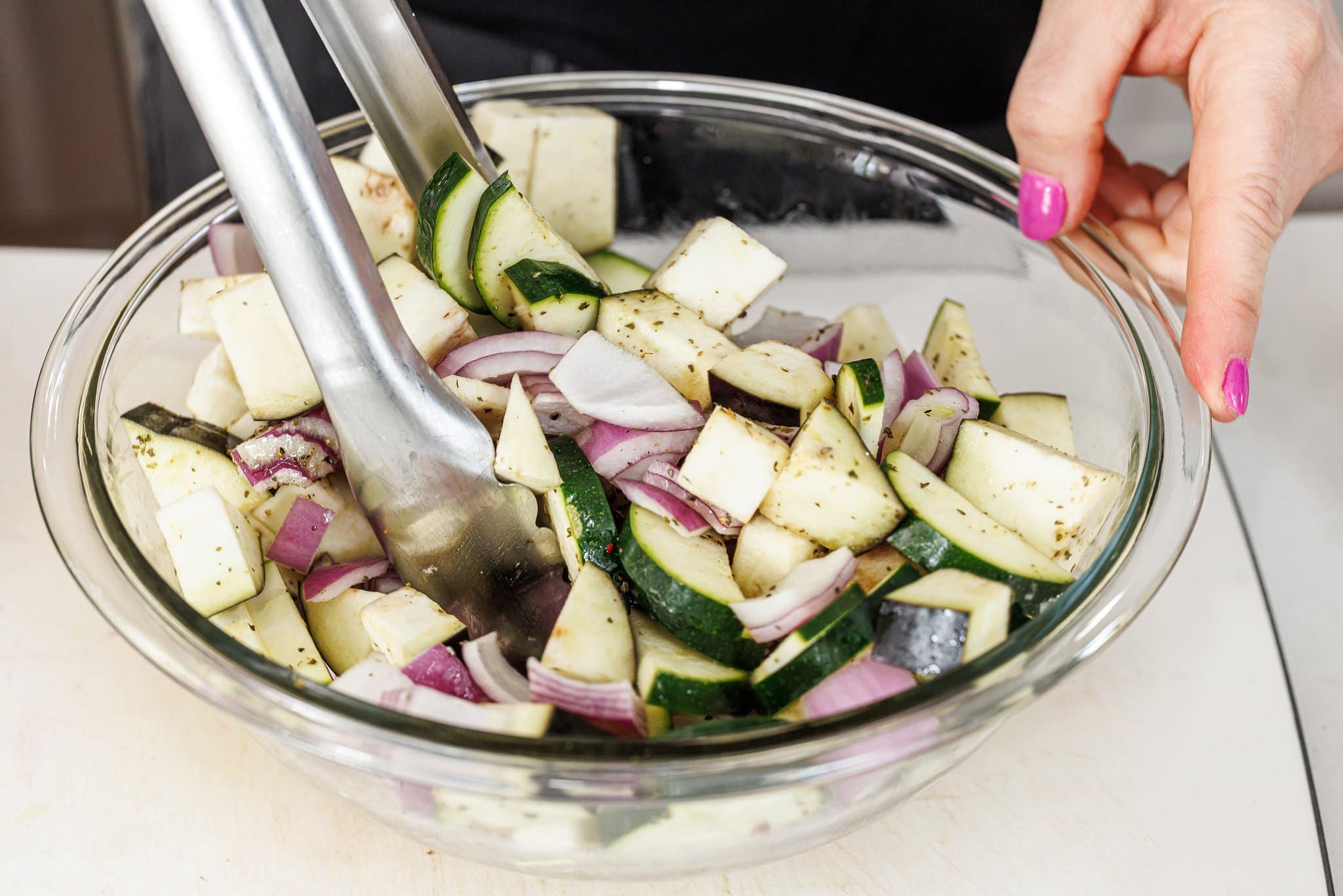 Tossing chopped veggies in olive oil and seasoning.
