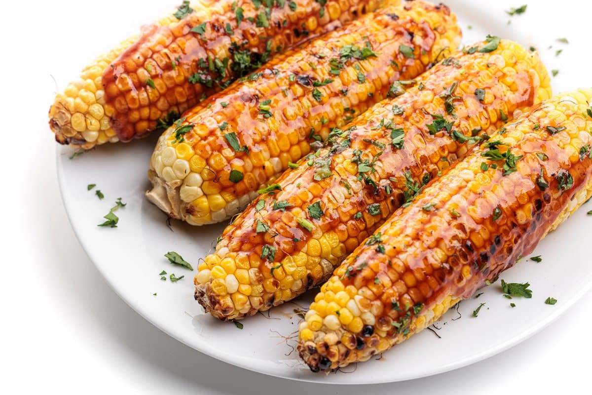 Healthy barbecue recipes, grilled corn on the cob with bbq sauce.