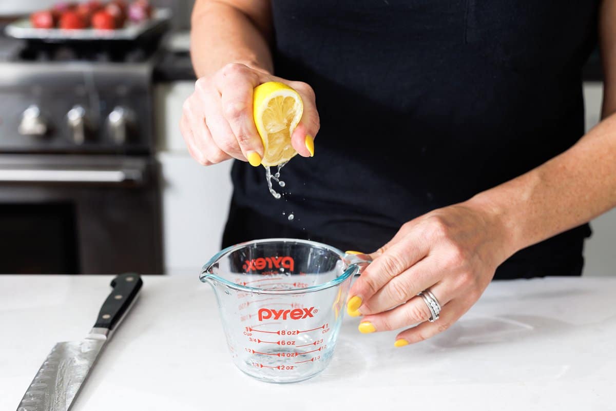 Squeezing lemon juice into a measuring cup.