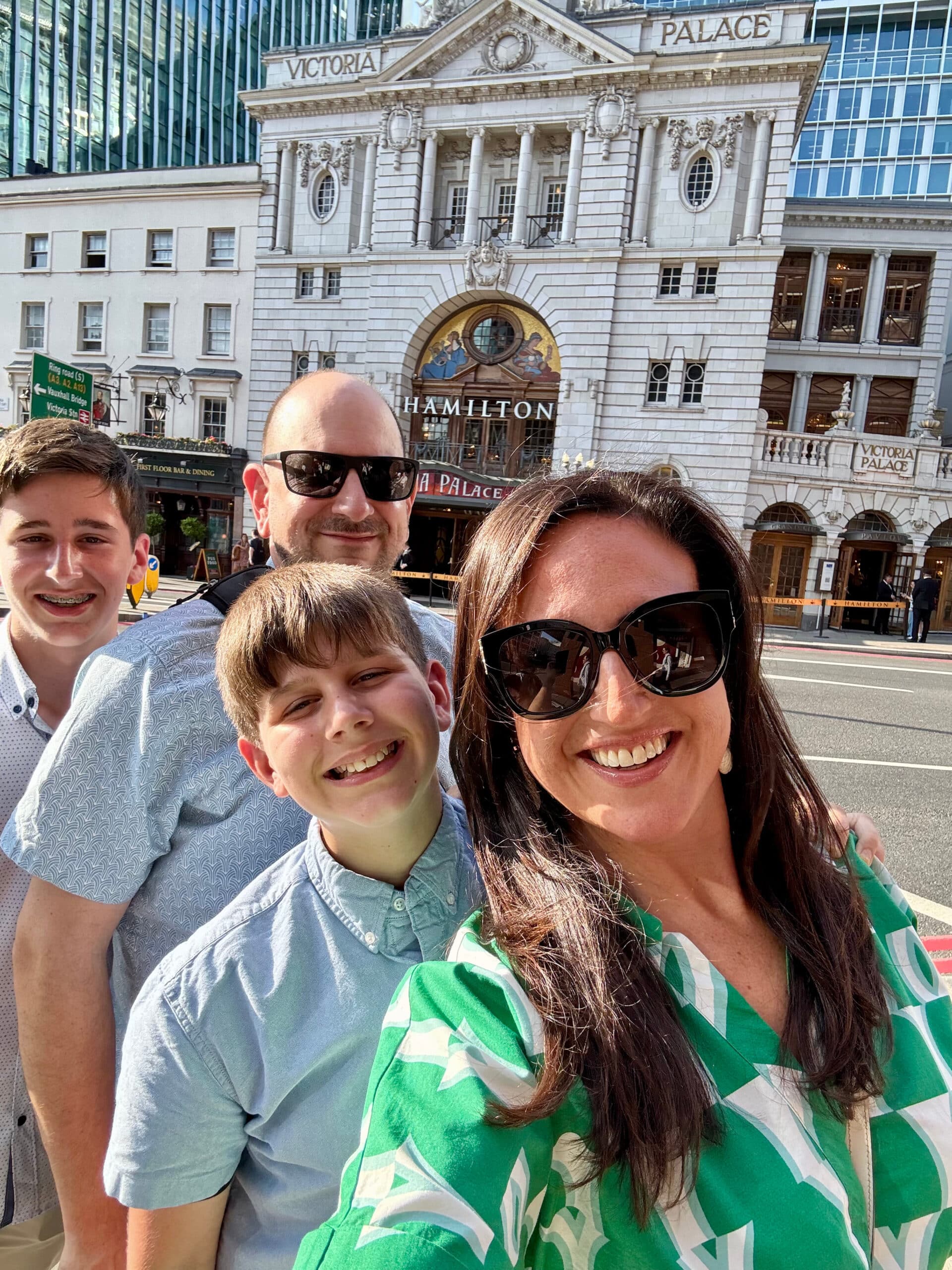 Liz and family standing in front of the Victoria Palace in London.