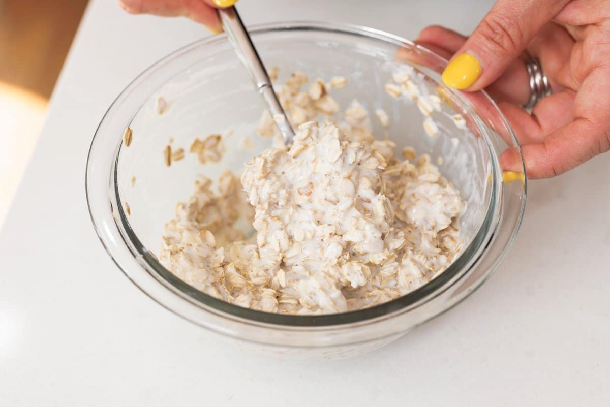 Mixing yogurt, milk, and oats in a bowl.