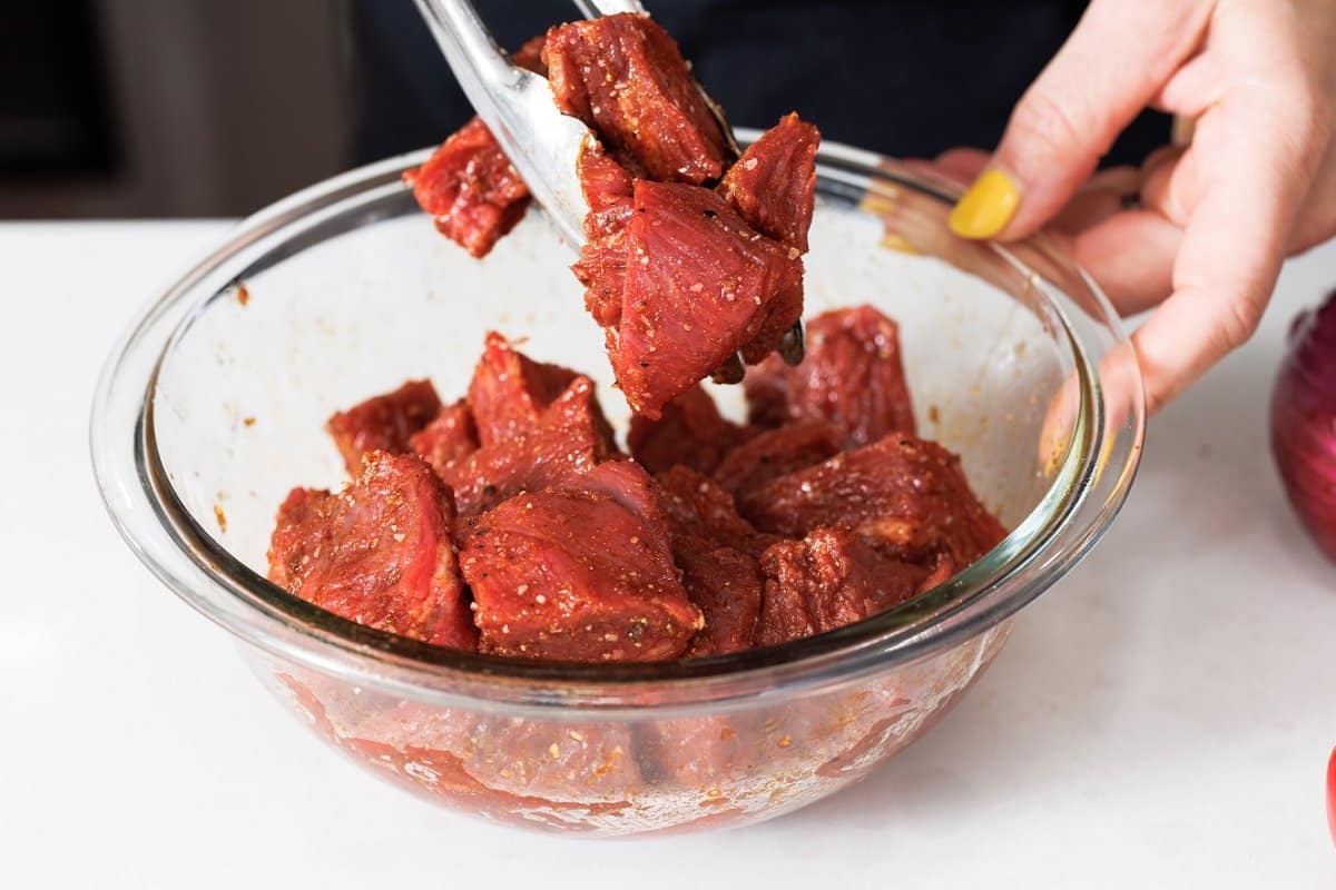 Tossing steak in spices.