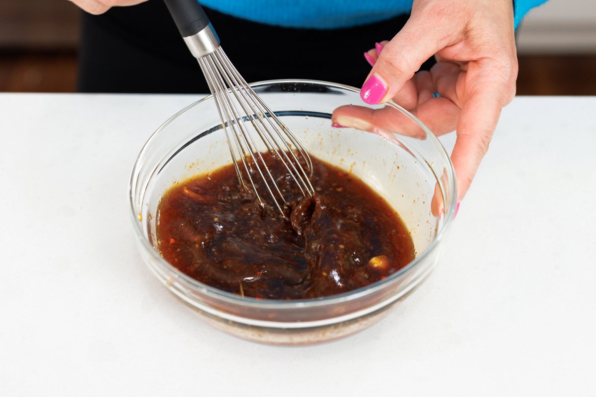 Whisking teriyaki sauce in bowl.