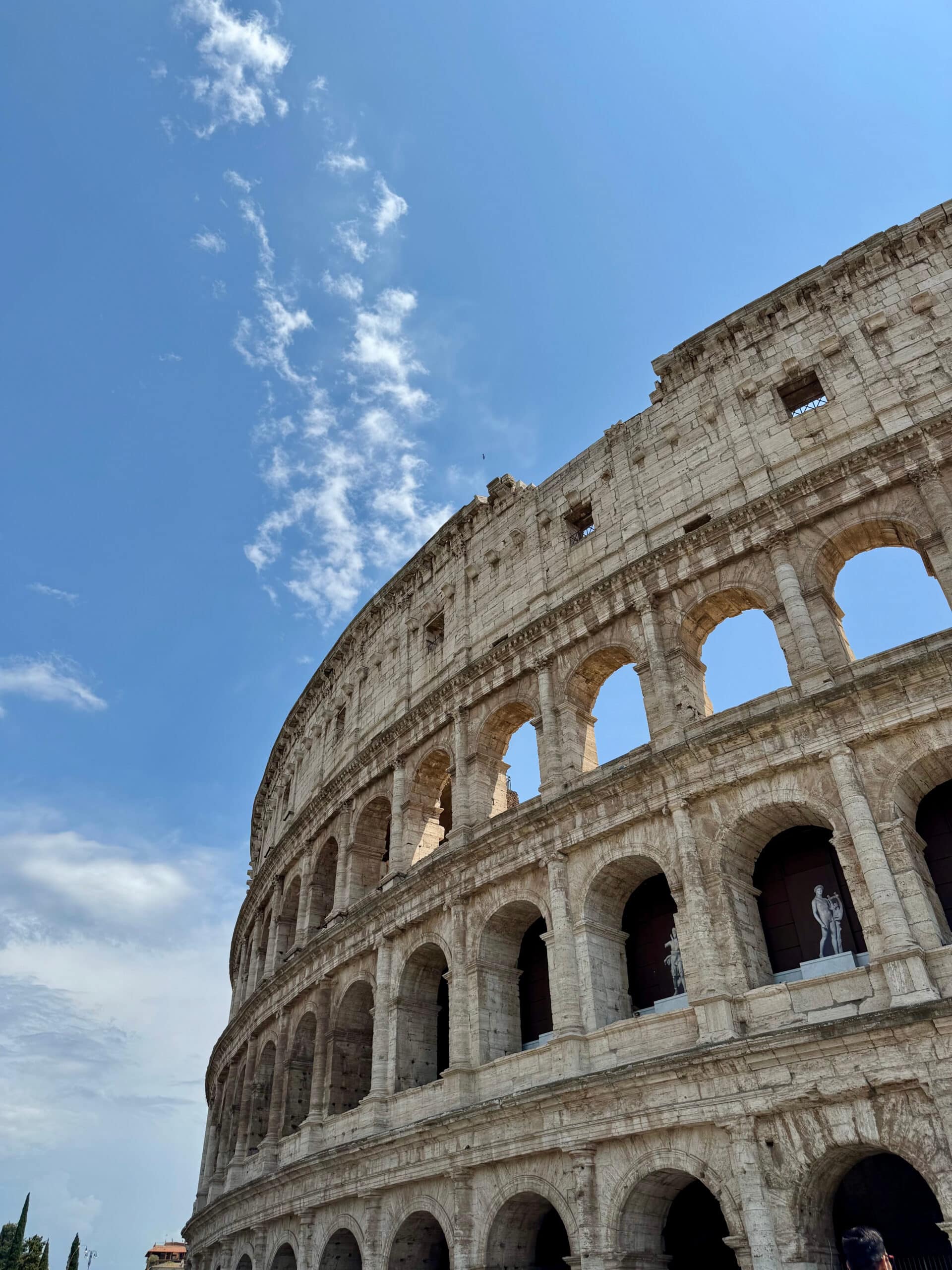 View of the side of the colosseum in front of a blue sky.