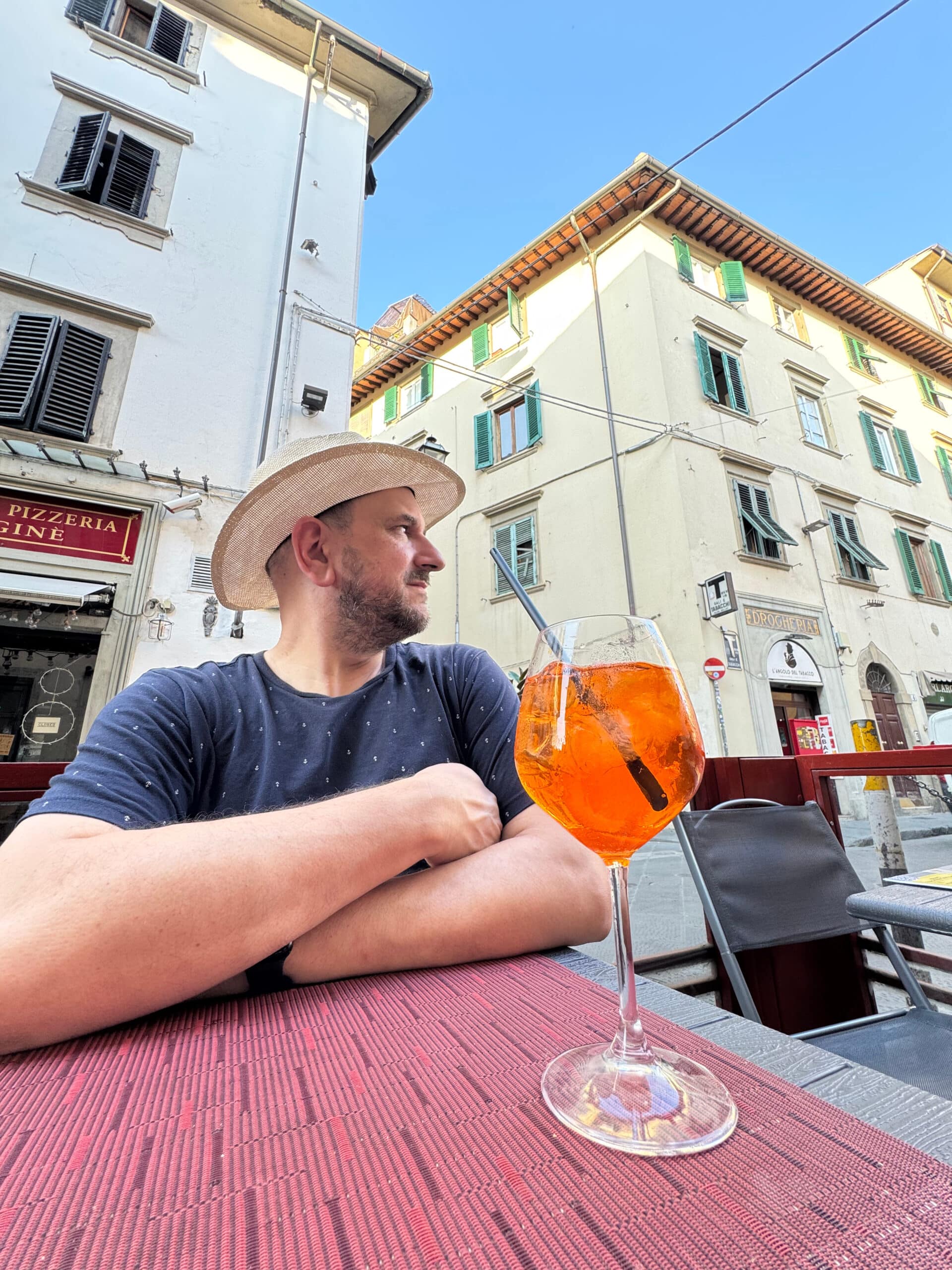 Rich sitting at an outdoor table enjoying an aperol spritz.