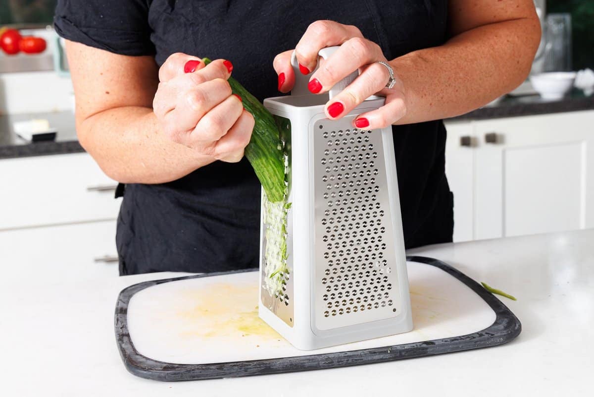 Grating a cucumber on a cutting board.