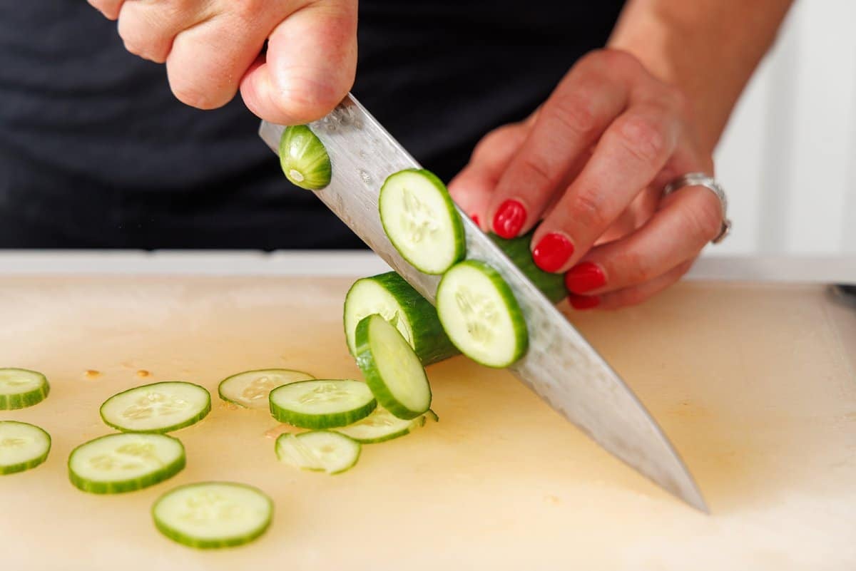 Liz slicing cucumber with a sharp knife.