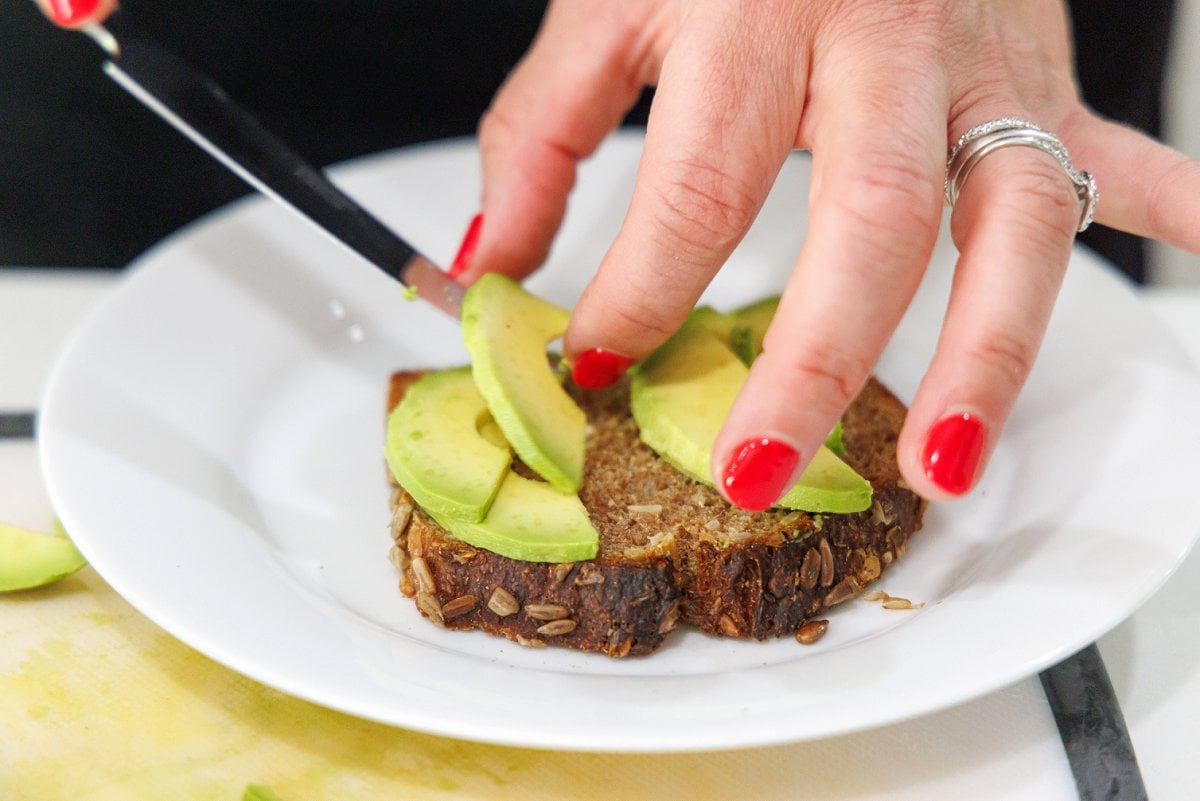 Layering avocado on toasted bread.