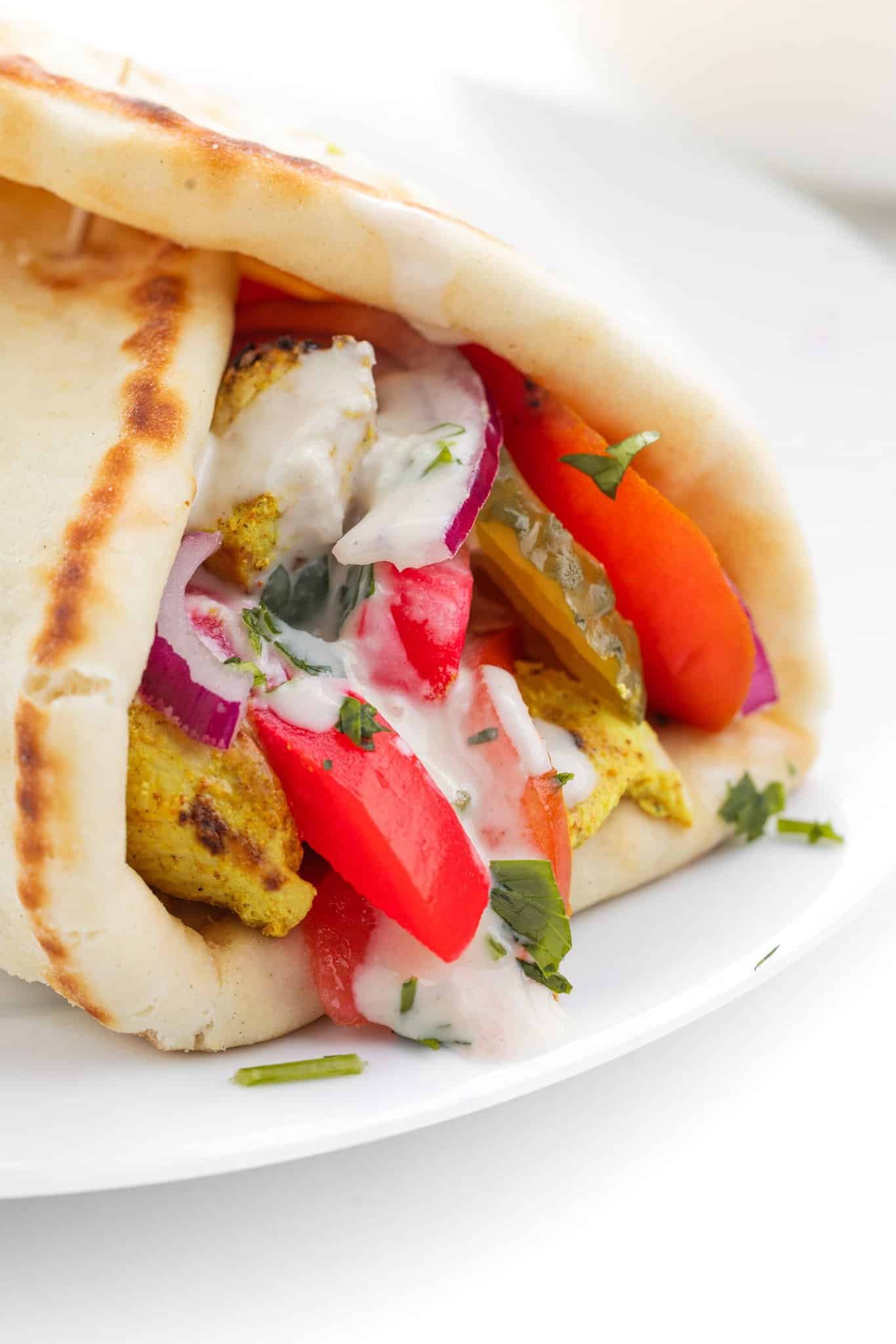 A chicken shawarma naan wrap with tahini sauce dripping out the top.