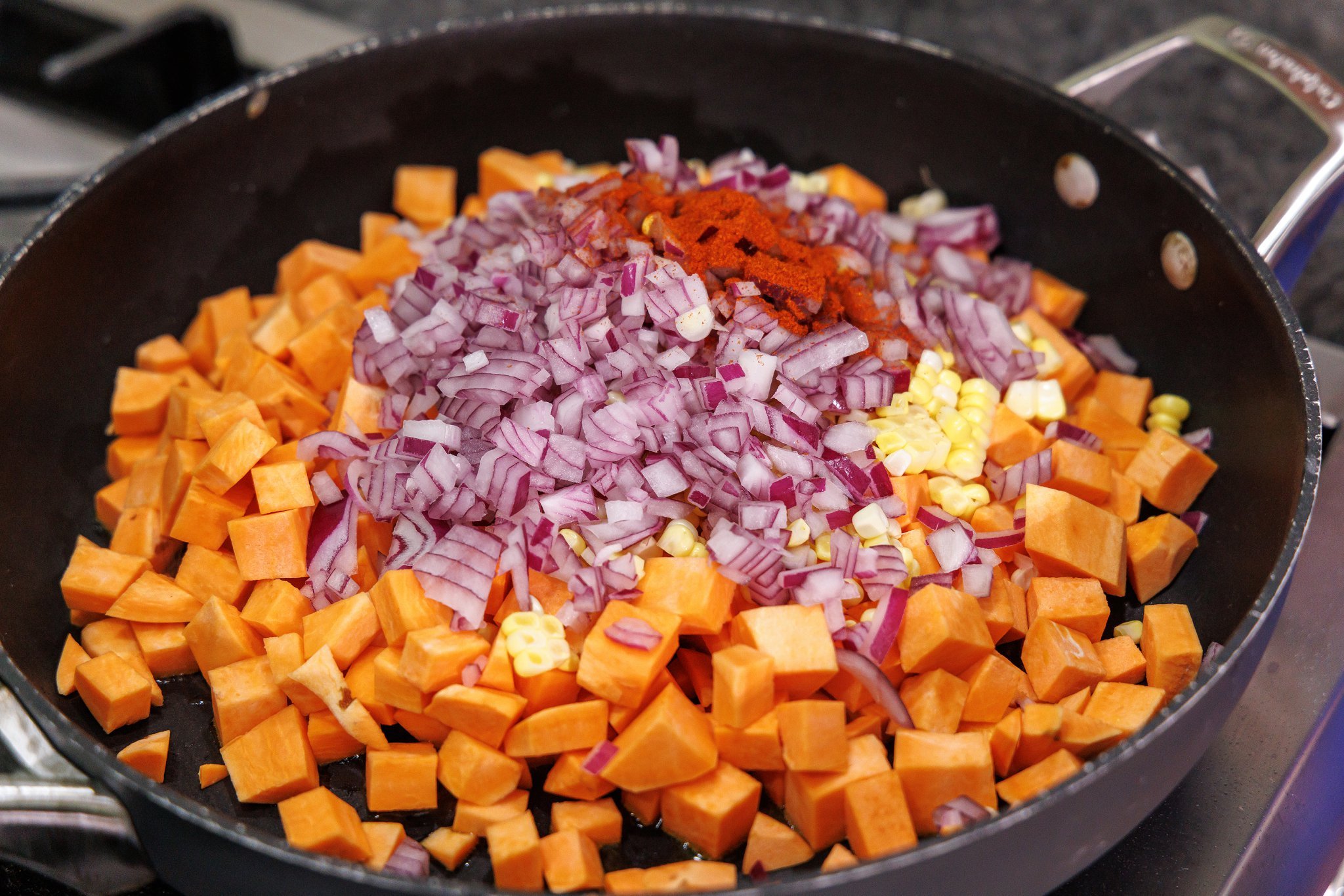 Sweet potato, corn, and red onion added to cast iron skillet.