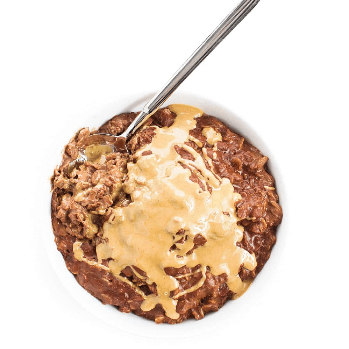 Chocolate oatmeal drizzled with melted peanut butter in a bowl with a spoon.