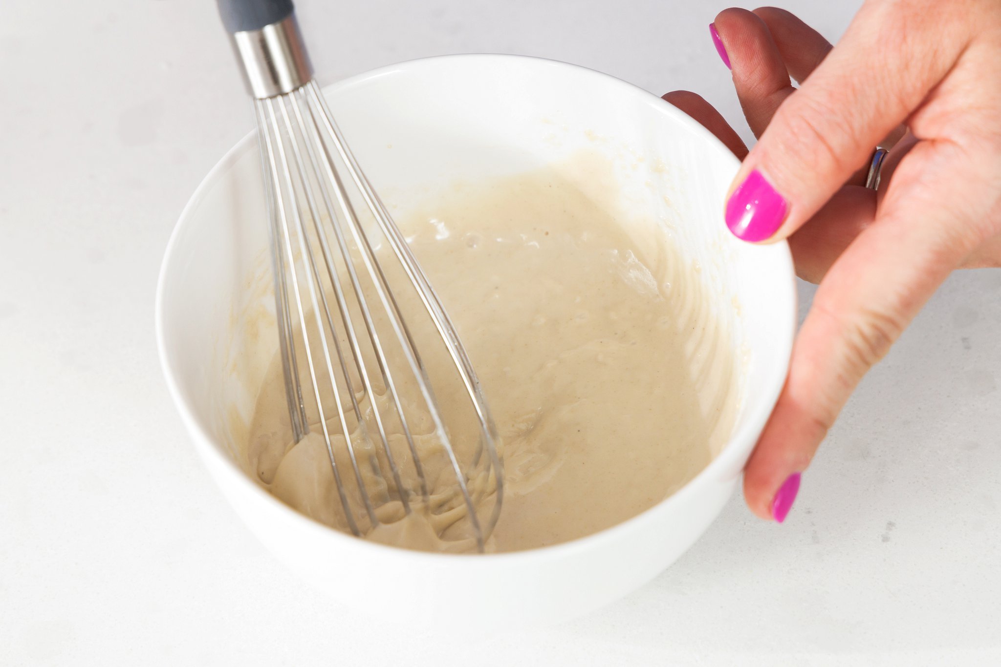 Whisking together tahini sauce.