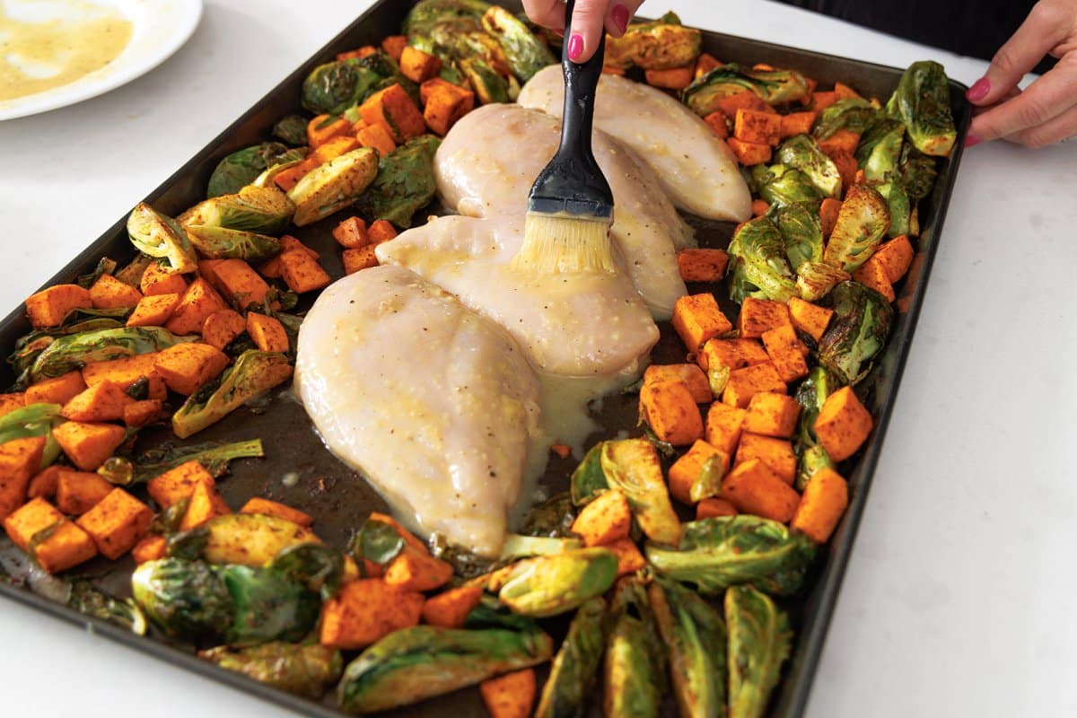 Maple dijon chicken added to sheet pan with roasted veggies.