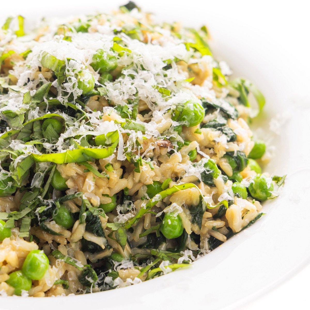Brown rice with spinach and herbs garnished with fresh parmesan cheese shavings.