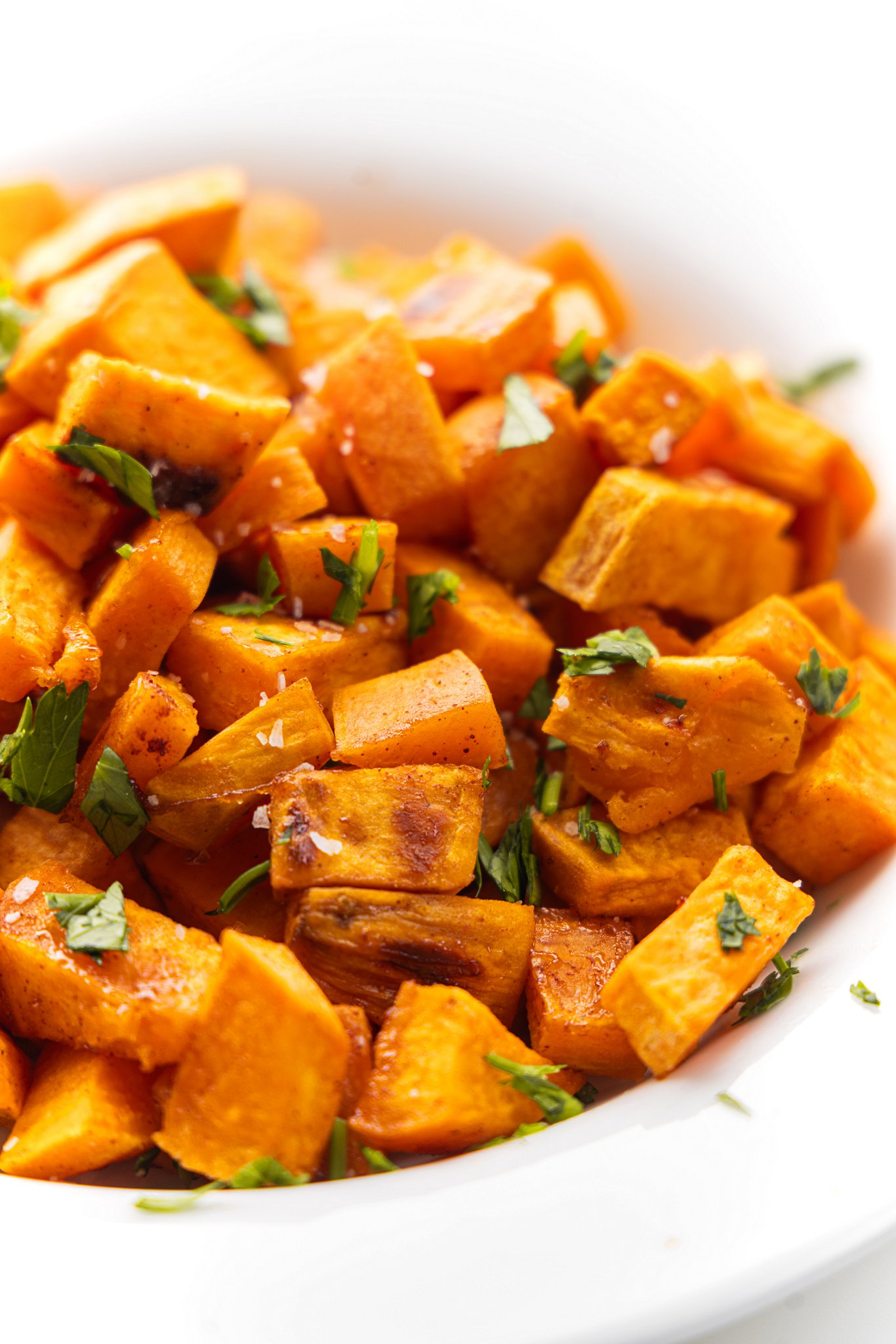 Salted maple roasted sweet potatoes garnished with fresh parsley.