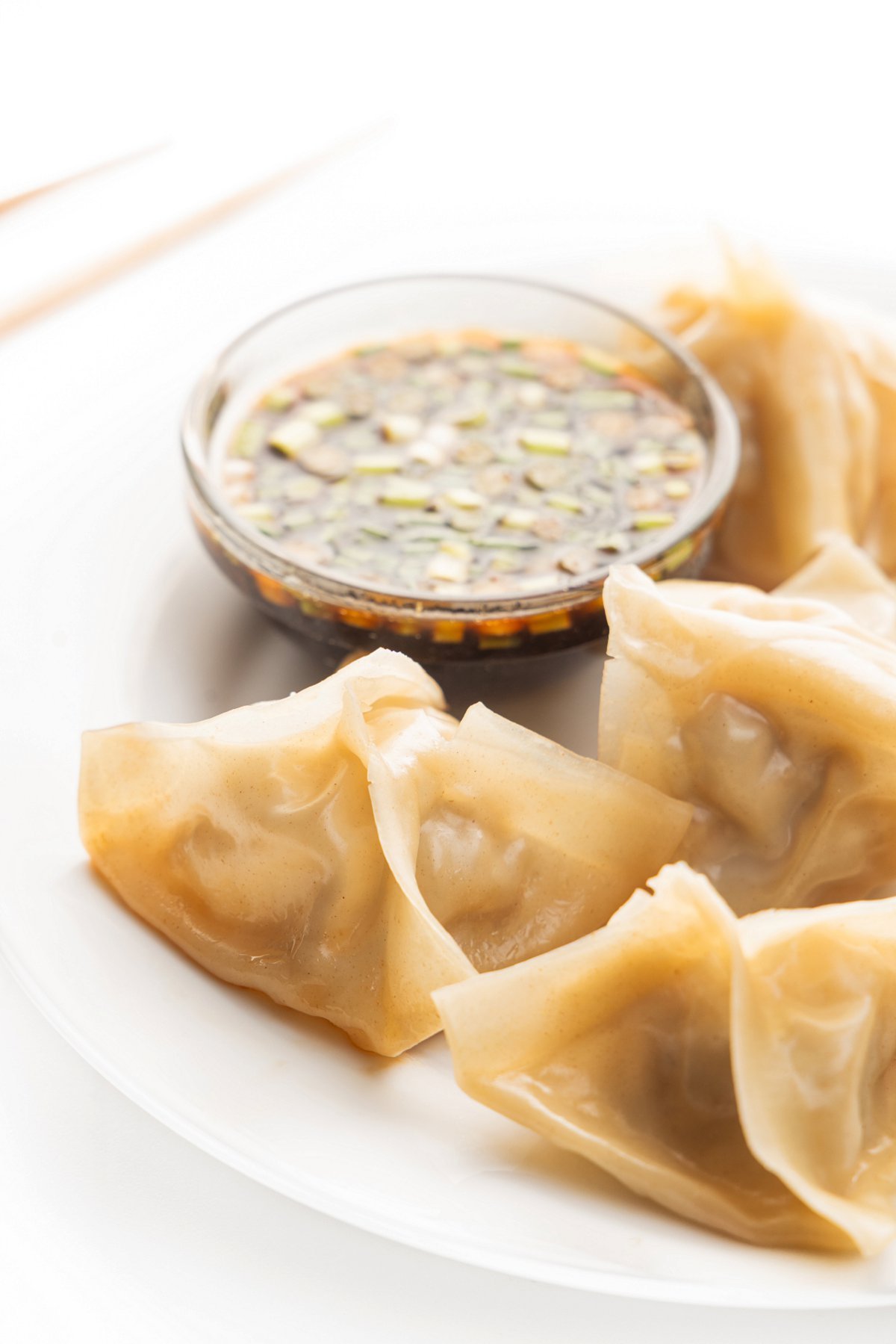 Close up of 4 steamed pork dumplings on a white plate.