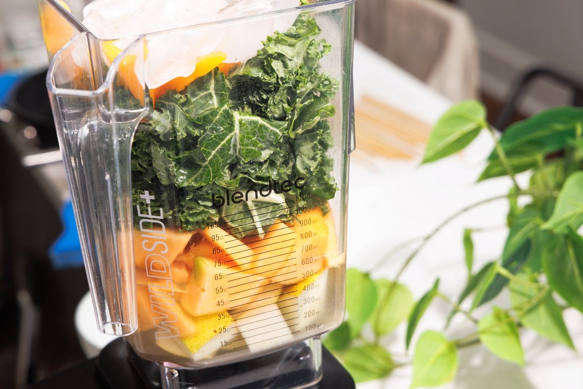 Fruit and vegetables piled high in a blender.